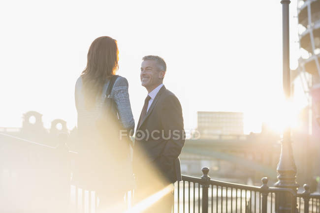 Бізнесмен і бізнес-леді розмовляють на сонячних міських перилах — стокове фото
