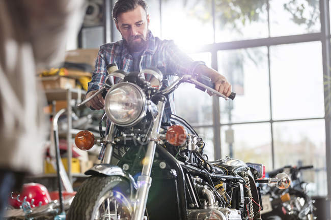 Male motorcycle mechanic working on motorcycle in workshop — Stock Photo