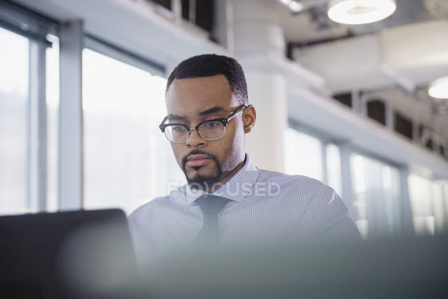 Homme d'affaires sérieux et concentré travaillant à l'ordinateur portable dans le bureau — Photo de stock