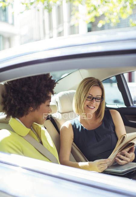 Бизнесвумен читает газету на заднем сидении автомобиля — стоковое фото