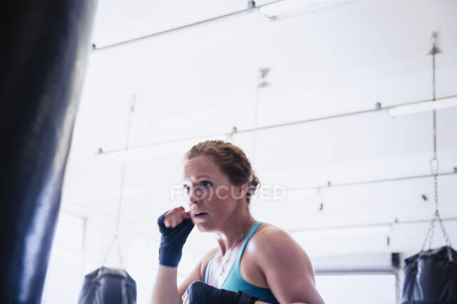 Решительная женщина боксер бокс на боксерскую грушу в тренажерном зале — стоковое фото