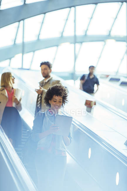 Mujer usando tableta digital en escaleras mecánicas - foto de stock