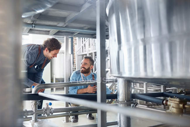 Male brewers talking vat in brewery — Stock Photo