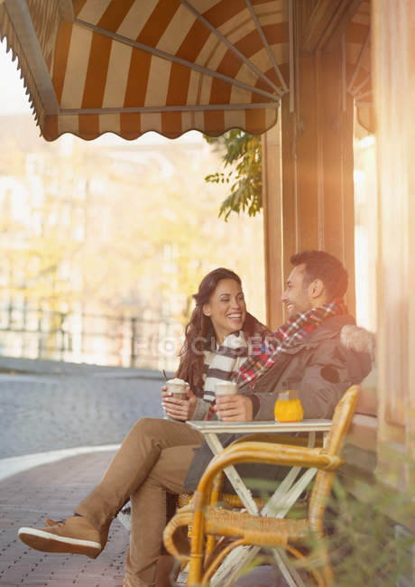 Young couple drinking milkshakes at sidewalk cafe — Stock Photo