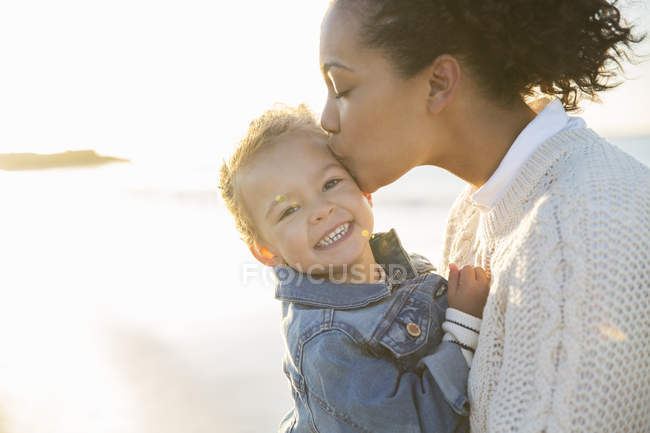 Mutter küsst Tochter am Strand — Stockfoto