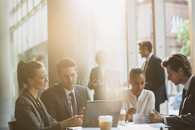 Geschäftsleute, die am Laptop arbeiten und Papierkram in Besprechungen überprüfen — Stockfoto