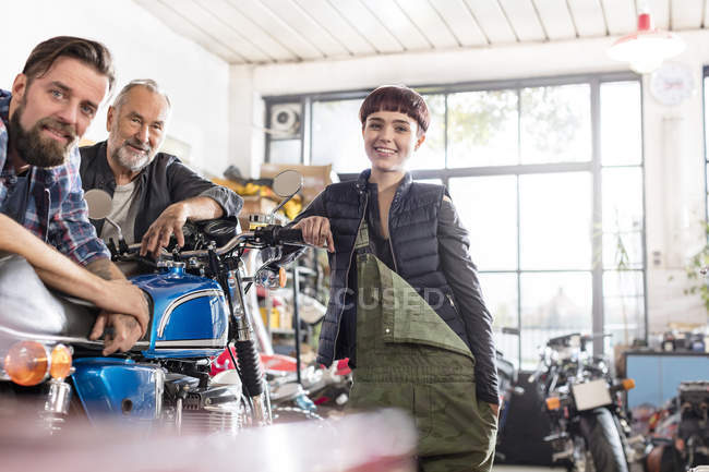 Портрет улыбающихся мужчин и женщин механики мотоциклов в мастерской — стоковое фото