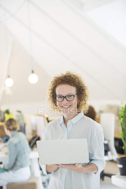 Ritratto di donna che tiene il computer portatile in ufficio — Foto stock