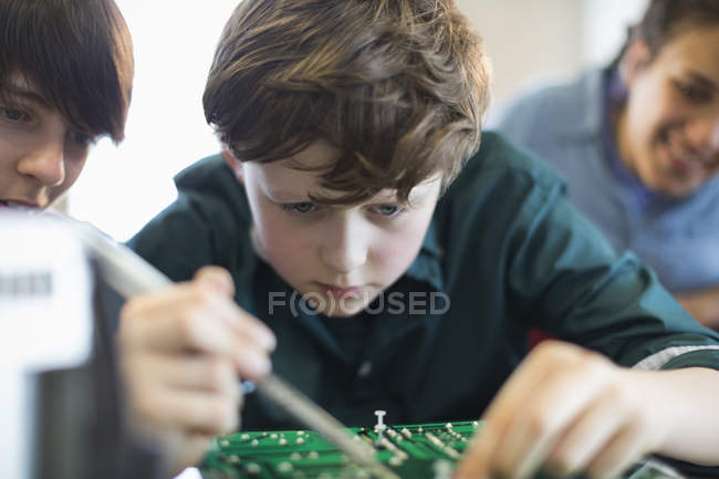 Focused boy student assembling electronics in classroom — Stock Photo