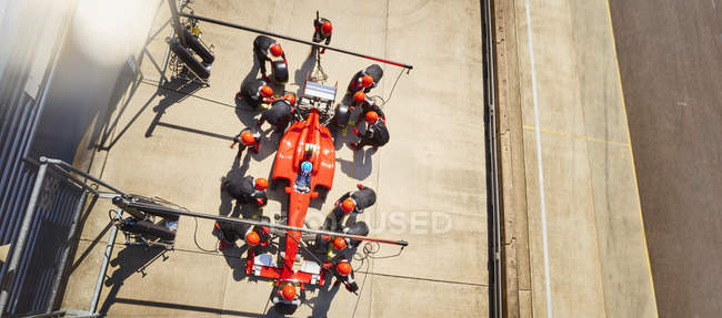 Tripulación aérea trabajando en la fórmula uno coche de carreras en pit lane - foto de stock