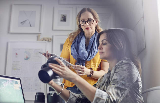 Female photographers with digital camera and digital tablet in office — Stock Photo
