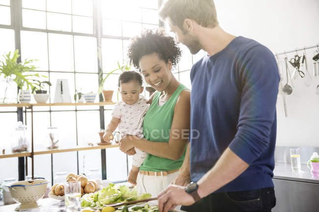 Familia feliz preparando la comida en la cocina doméstica - foto de stock