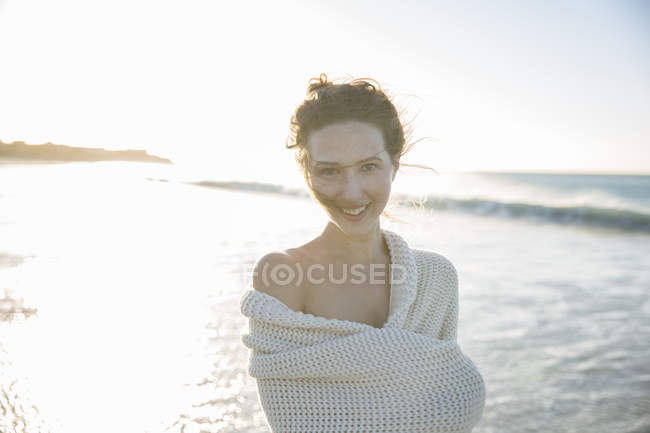 Портрет молодой женщины, завернутой в одеяло на пляже — стоковое фото