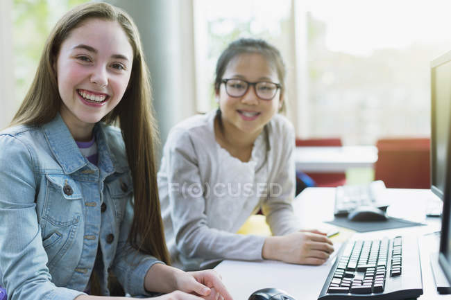 Retrato sonriente, estudiantes de confianza investigando en la computadora en la biblioteca - foto de stock