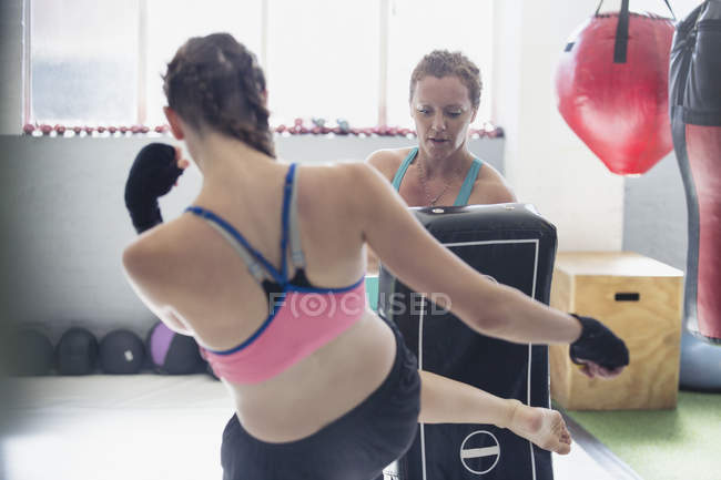 Female boxers kickboxing with padding in gym — Stock Photo