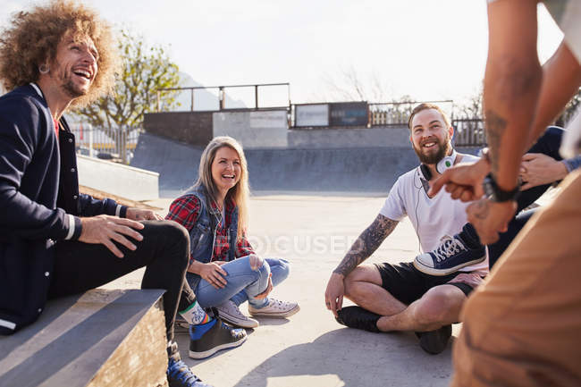 Amigos conversando e saindo no ensolarado parque de skate — Fotografia de Stock