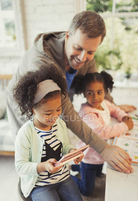 Padre e hijas multiétnicos con tableta digital - foto de stock