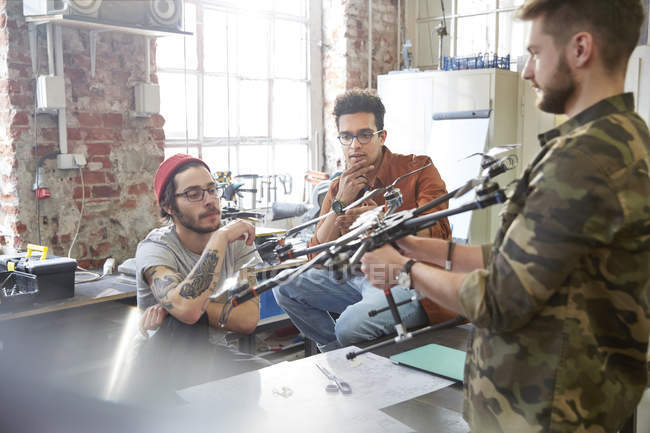 Reunión de diseñadores, examinando drones en taller - foto de stock