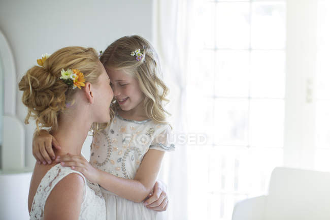 Bride and bridesmaid facing each other and smiling in bedroom — Stock Photo