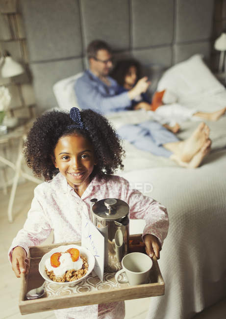 Портрет улыбающейся девушки, подающей завтрак на День отца в постели с отцом — стоковое фото