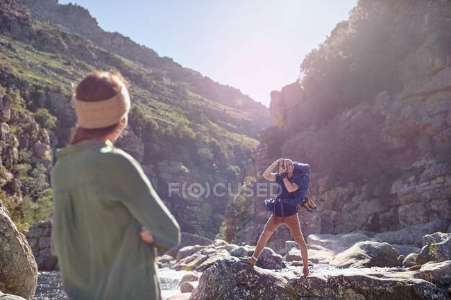 Junge Frau beobachtet Freund beim Wandern und fotografiert schroffe Klippen — Stockfoto