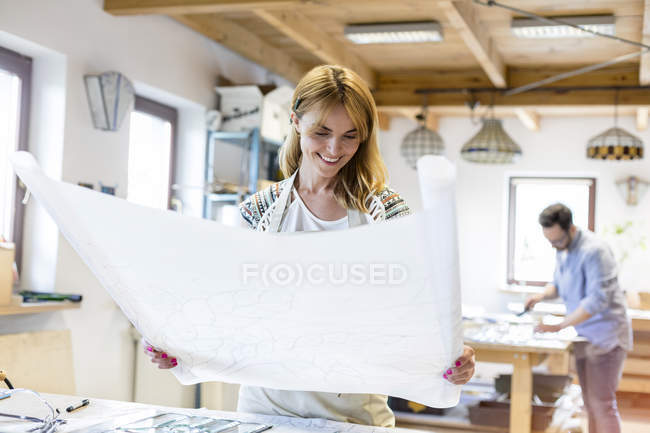 Stained glass artist reviewing blueprint drawings in studio — Stock Photo