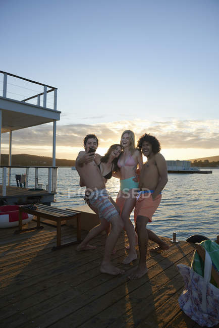 Playful young adult friends taking selfie with camera phone on summer houseboat — Stock Photo