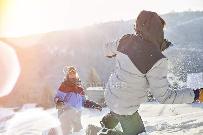 Грайлива пара, насолоджуючись сніжною битвою в сонячному сніжному полі — стокове фото