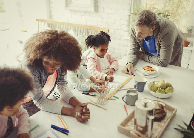 Coloration multiethnique de la jeune famille avec des marqueurs à table — Photo de stock
