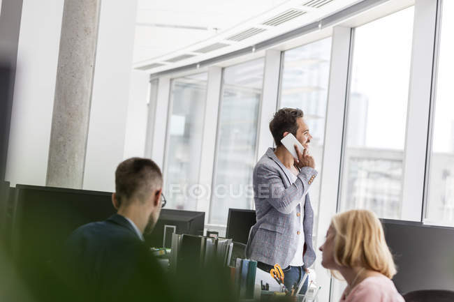 Бизнесмен разговаривает по мобильному телефону у окна офиса — стоковое фото