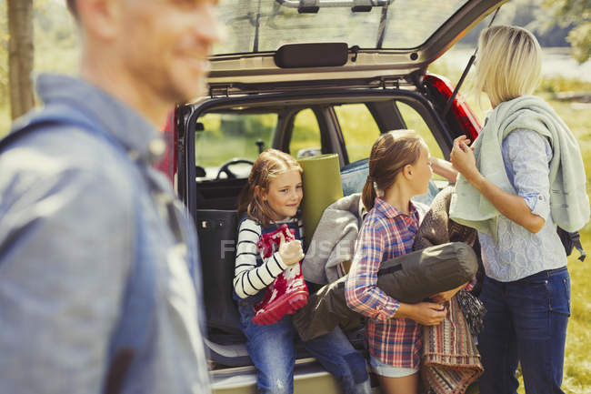 Family unloading camping equipment from car — Stock Photo