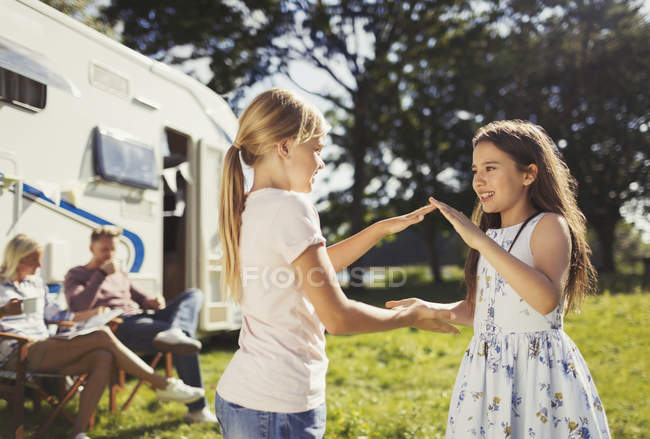 Sorelle che giocano a pat-a-cake fuori dal camper soleggiato — Foto stock