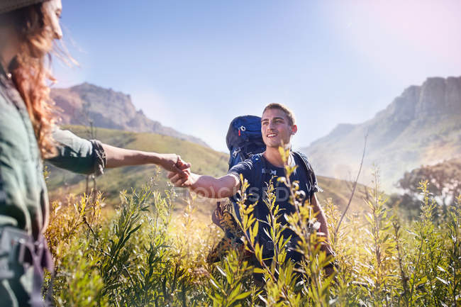 Young couple holding hands hiking in sunny valley — Stock Photo