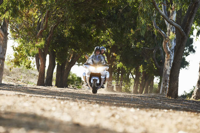Couple à moto sur route bordée d'arbres — Photo de stock