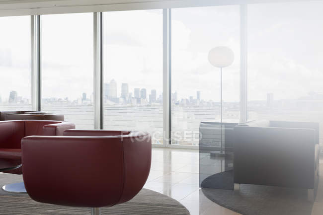 Chaises en cuir et canapé dans le salon de bureau urbain moderne avec vue sur la ville — Photo de stock