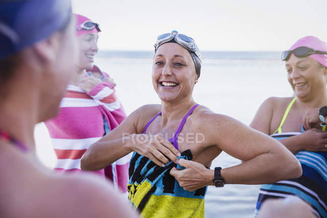 Lächelnde aktive Schwimmerinnen mit Handtüchern im Meer — Stockfoto