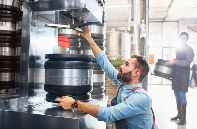 Male brewer filling kegs in brewery — Stock Photo