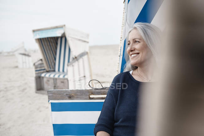 Mujer mayor sonriente mirando hacia la playa - foto de stock