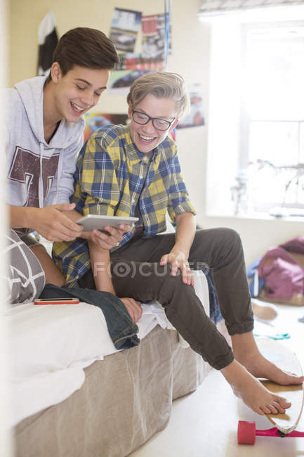 Двоє хлопчиків-підлітків, які діляться цифровим планшетом у кімнаті — стокове фото