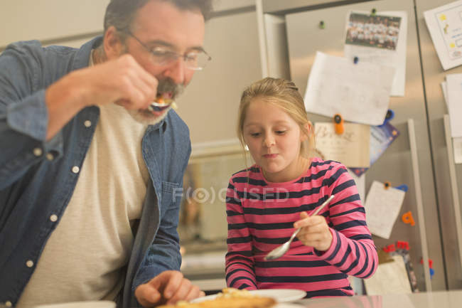 Батько і дочка їдять пиріг на кухні — стокове фото