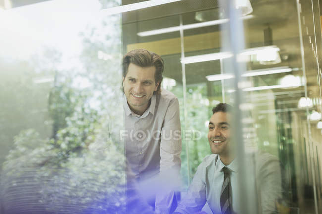 Hombres de negocios sonrientes en la reunión de la sala de conferencias - foto de stock