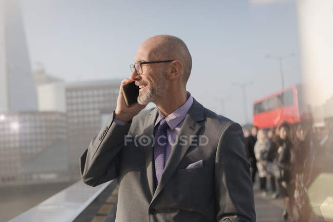 Businessman talking on cell phone on sunny urban bridge, London, UK — Stock Photo