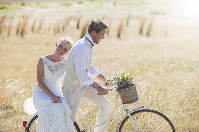 Feliz jovem casal andar de bicicleta no prado — Fotografia de Stock