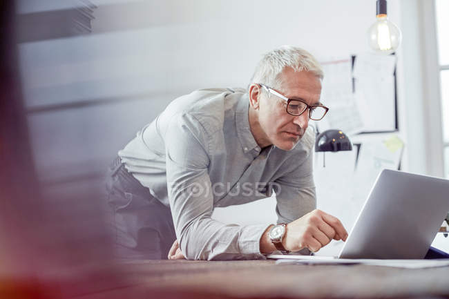 Hombre de negocios serio y enfocado que trabaja en la computadora portátil en la oficina - foto de stock