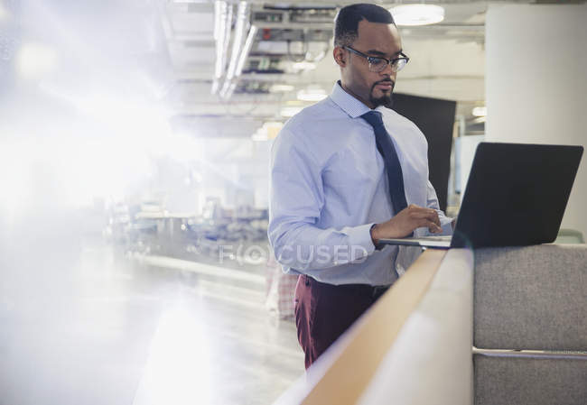 Businessman using laptop at office cubicle wall — Stock Photo