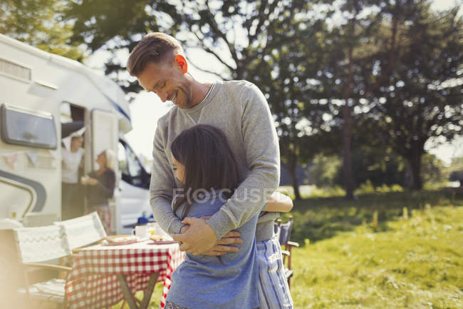 Sonriente padre abrazando hija fuera soleado autocaravana - foto de stock