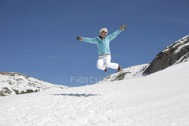 Femme exubérante sautant dans la neige — Photo de stock
