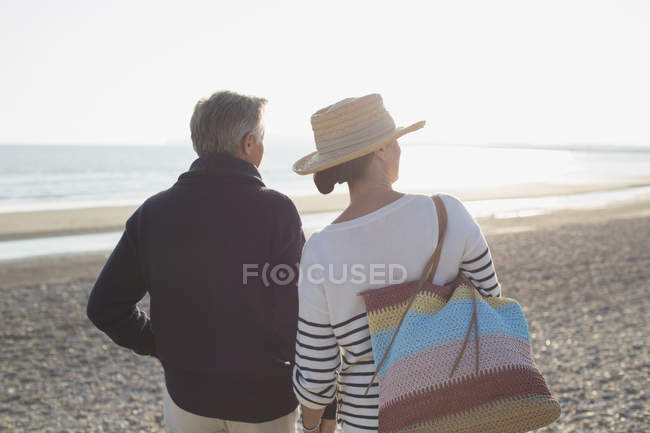 Casal maduro olhando maneira na praia pôr do sol — Fotografia de Stock