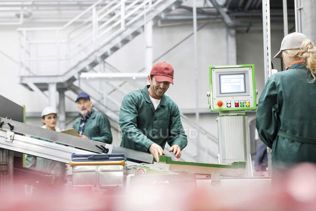 Travailleur souriant à la bande transporteuse dans l'usine de transformation des aliments — Photo de stock