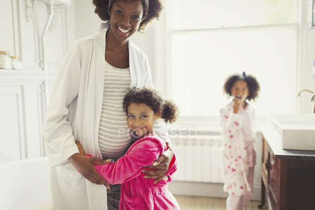Porträt lächelnde schwangere Mutter und Töchter im Badezimmer — Stockfoto